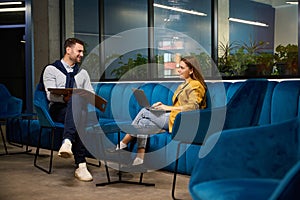Colleagues man and woman sit on a comfortable blue sofa