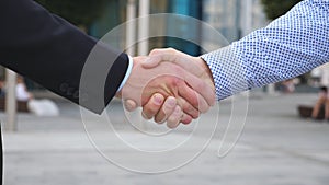 Colleagues meet and shake hands in the city background. Two businessmen greeting each other in urban environment