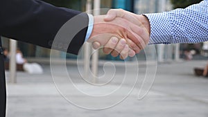 Colleagues meet and shake hands in the city background. Two businessmen greeting each other in urban environment