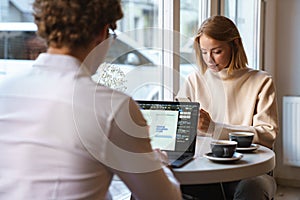 Colleagues sit in cafe using laptop computer