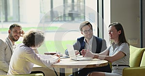 Colleagues sit in modern office laughing, brainstorm, discuss business