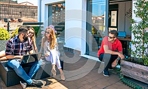 Colleagues talking in a coffee break while man watering plants in office rooftop