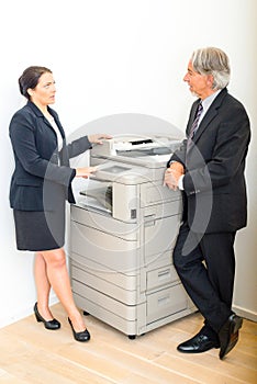 Colleagues talking at copying machine in the