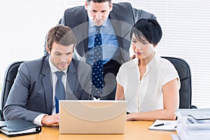 Colleagues using laptop at office desk