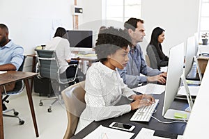 Colleagues work at computers in open plan office, side view