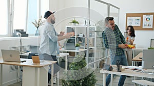 Colleagues young men and women enjoying toy guns fight in office having fun laughing