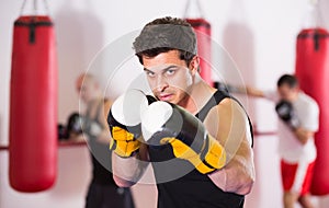 Collected sportsman in the boxing hall practicing boxing punches