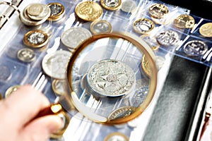 Old numismatics silver coins with magnifying glass photo