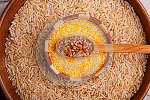 Collecting dry cereals. Buckwheat, rice, wheat in a large brown plate.