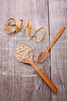 Collecting dry cereals. On a wooden background in spoons oatmeal and buckwheat.