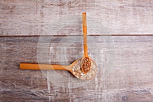 Collecting dry cereals. On a wooden background in spoons oatmeal and buckwheat.