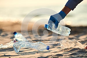 Collecting plastic bottles on sea beach. Cleaning environmental pollution