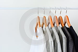 Collection of black, gray and white color hanging on wooden clothes hanger in closet or clothing rack