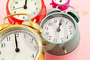 Collection of bright colorful alarm clocks over the pink background