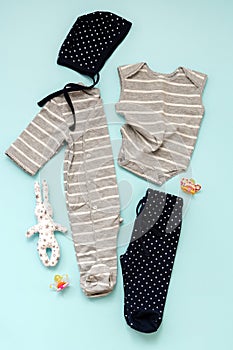 Collection of children`s clothes for the newborn boy and girl on a blue background: body to choose, cap, pants.