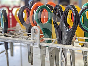 A collection of classroom scissors upside down in a rack