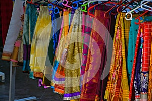 Collection of colorful sarees hanging in hangers in Indian shop