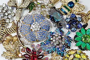 Collection of colorful vintage rhinestone brooches, on white