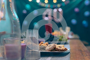 Collection of cookies and other food on a party table at a birthday event with visible baloons in the background. Focus on cookies