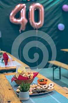 Collection of cookies and other food on a party table at a birthday event with visible baloons in the background. Focus on cookies