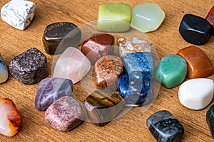 Collection of different colored polished gemstones an jewels luxury on wooden underground