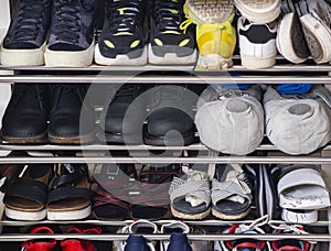 A collection of different shoes and sneakers of one family in a shoe rack