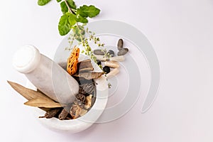 Collection of different spices and herbal tablets with tulsi leaves in white mortar pestle on white background. Herbal and