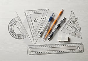 A collection of drafting tools on a light wooden surface includes a