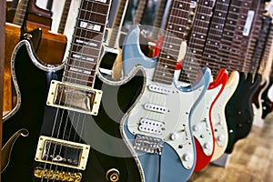 A collection of electric solid body guitars hanging in a row