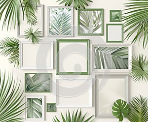 A collection of empty white picture frames of various sizes arranged haphazardly on a bed of lush tropical leaves.