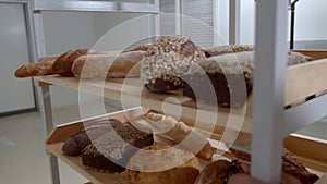 Collection of fresh baked breads is on the wooden shelves of  cart in a bakery