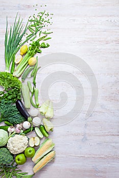 Collection of fresh green vegetables on white rustic background.