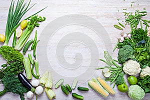 Collection of fresh green vegetables on white rustic background.