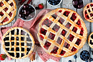 Collection of homemade fruit pies over a rustic white wood table background