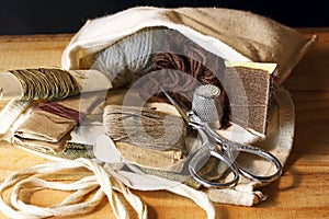 COLLECTION OF ITEMS IN A DARNING AND SEWING MILITARY REPAIR KIT CONTAINED IN A WHITE CLOTH BAG