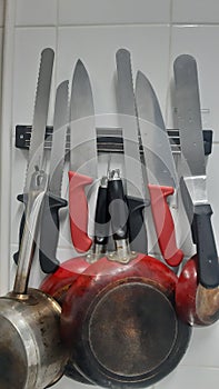 collection of kitchen knives and bread knives along with pots that are regularly stored in their places