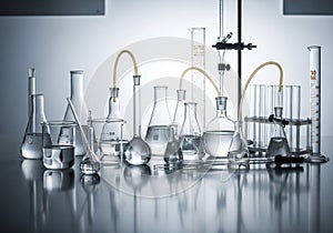 A collection of laboratory glassware arranged on a reflective surface. Includes beakers, flasks,