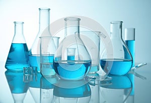 A collection of laboratory glassware filled with blue liquid on a reflective