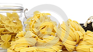 Collection from mixed uncooked raw pasta - spaghetti, farfalle, tagliatelle and black spaghetti