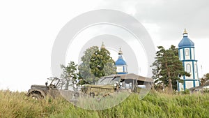Collection of old military automobiles made in USSR. Retro vehicles standing on field against church. Old russian cars
