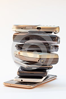 collection of old mobile phones stacked, piled in front of white background