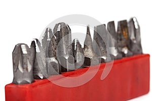 Collection of old rusty bit holders for a drill in a red case isolated on white background, macro, closeup