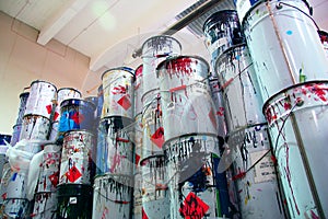 A collection of paint cans, glue buckets, mastic and toxic and hazardous material stacked