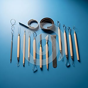 A collection of pottery and sculpting tools is arranged on a blue surface