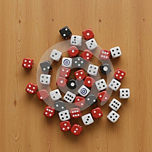 A collection of red, white, and black dice scattered on a wooden surface. The dice