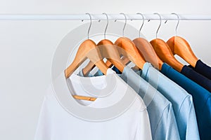 Collection shade of blue tone color t-shirts hanging on wooden clothes hanger in closet photo