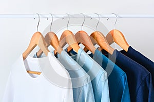 Collection shade of blue tone color t-shirts hanging on wooden clothes hanger on clothing rack