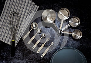 Collection of stainless  measuring cups and measuring spoon with a plate