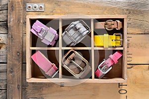 Collection of stylish belts in wooden crate