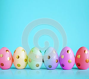 Collection of stylish colors eggs with golden circles for Easter celebration on blue background.